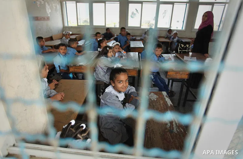 A Palestinian girl looks out of a classroom window as she attends a lesson on the first day of a new school year, at a United Nations-run school in Khan Younis in the southern Gaza Strip August 28, 2016. Photo by Ashraf...