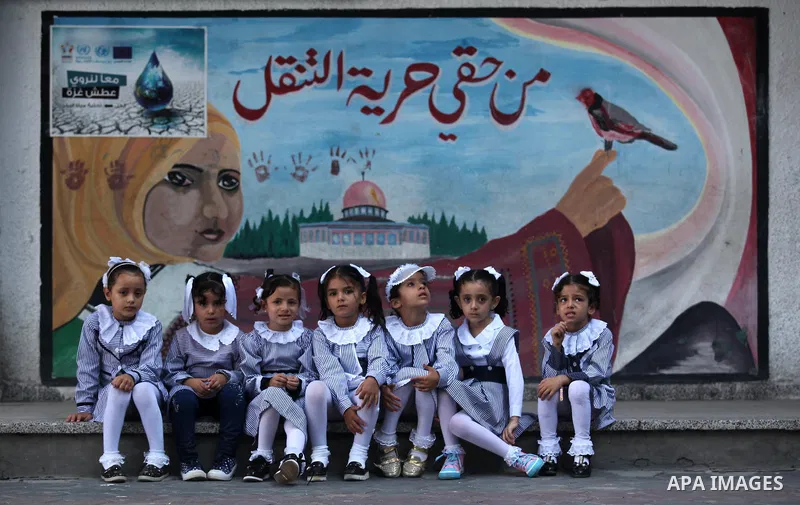 Palestinian schoolgirls sit in front of a mural on the first day of a new school year, at a United Nations-run school in Khan Younis in the southern Gaza Strip August 28, 2016. The mural reads, "Freedom of movement is my...