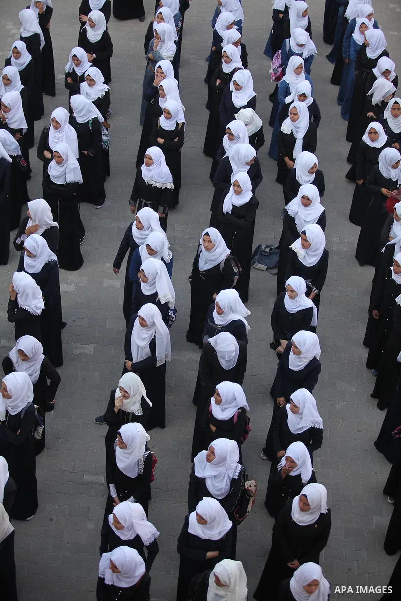 Palestinian schoolgirls play exercises inside their school in the morning of the first day of the new year study in Khan Younis in the southern Gaza Strip August 28, 2016. The mural reads. Photo by Ashraf Amra