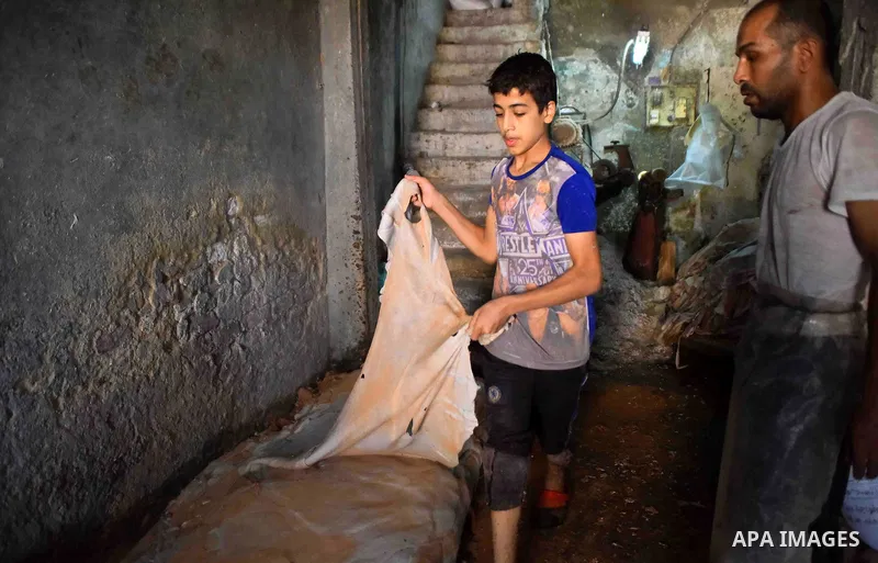 Egyptian leather tannery workers, salt the hides of animals before drying them, at a leather tannery, in Cairo, Egypt, on August 28, 2016. Photo by Amr Sayed
