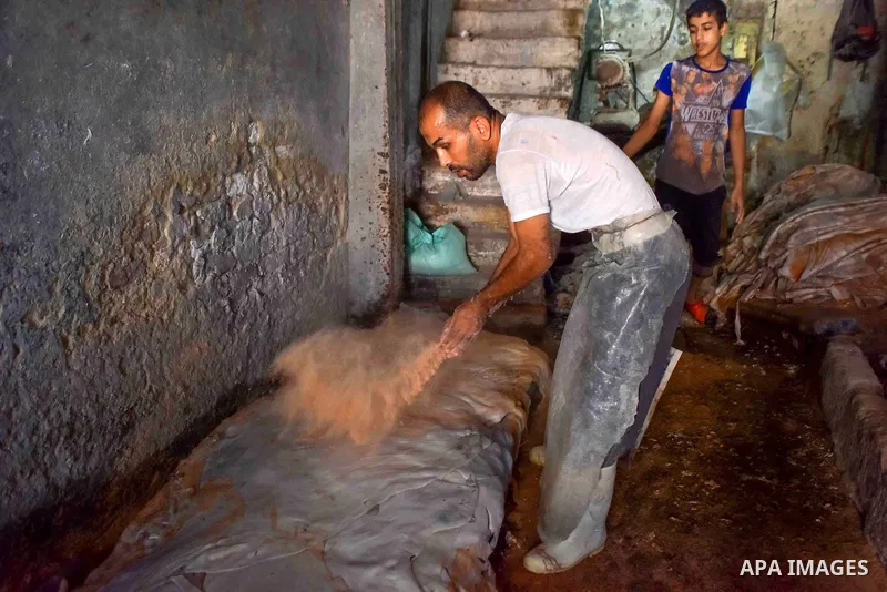 Egyptian leather tannery workers, salt the hides of animals before drying them, at a leather tannery, in Cairo, Egypt, on August 28, 2016. Photo by Amr Sayed