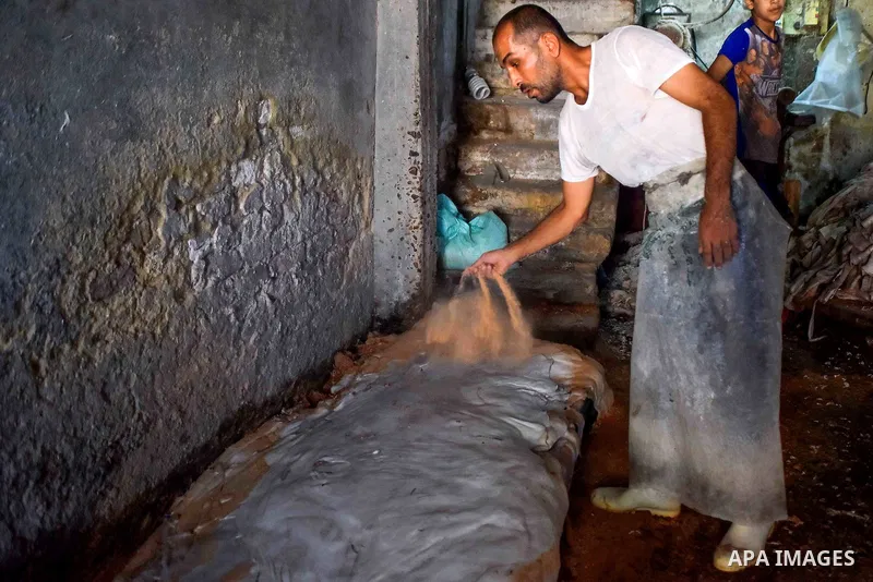 Egyptian leather tannery workers, salt the hides of animals before drying them, at a leather tannery, in Cairo, Egypt, on August 28, 2016. Photo by Amr Sayed