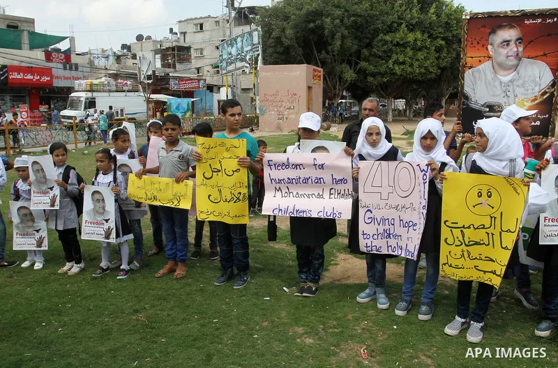 Palestinian demonstrators hold posters of Mohammad El Halabi, World Vision's manager of operations in Gaza who was accused by Israel of funnelling millions of dollars in aid money to Hamas, during a protest in solidarity...