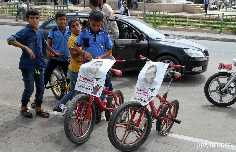 Palestinian demonstrators hold posters of Mohammad El Halabi, World Vision's manager of operations in Gaza who was accused by Israel of funnelling millions of dollars in aid money to Hamas, during a protest in solidarity...