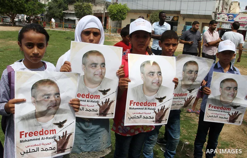 Palestinian demonstrators hold posters of Mohammad El Halabi, World Vision's manager of operations in Gaza who was accused by Israel of funnelling millions of dollars in aid money to Hamas, during a protest in solidarity...