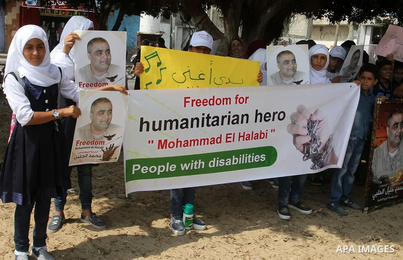 Palestinian demonstrators hold posters of Mohammad El Halabi, World Vision's manager of operations in Gaza who was accused by Israel of funnelling millions of dollars in aid money to Hamas, during a protest in solidarity...