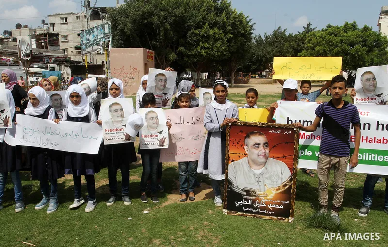 Palestinian demonstrators hold posters of Mohammad El Halabi, World Vision's manager of operations in Gaza who was accused by Israel of funnelling millions of dollars in aid money to Hamas, during a protest in solidarity...