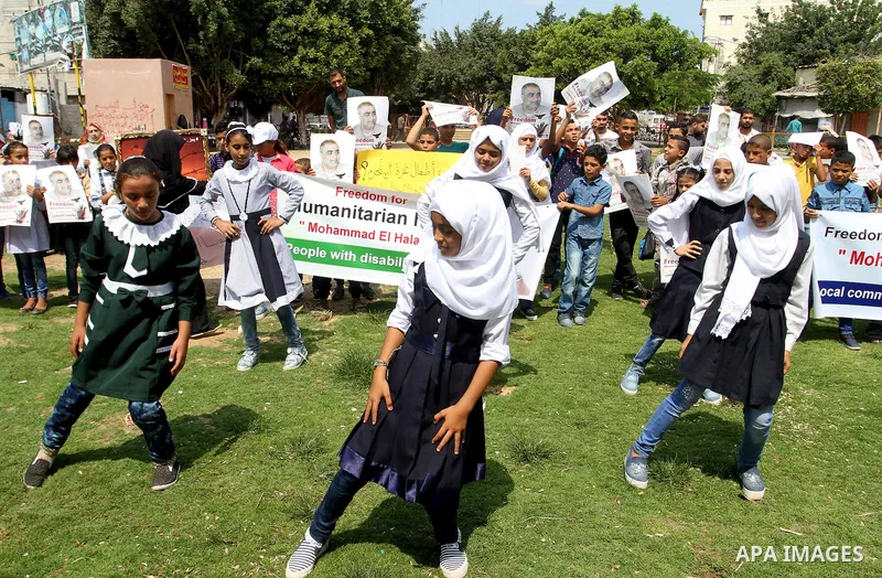 Palestinian demonstrators hold posters of Mohammad El Halabi, World Vision's manager of operations in Gaza who was accused by Israel of funnelling millions of dollars in aid money to Hamas, during a protest in solidarity...