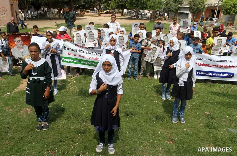 Palestinian demonstrators hold posters of Mohammad El Halabi, World Vision's manager of operations in Gaza who was accused by Israel of funnelling millions of dollars in aid money to Hamas, during a protest in solidarity...