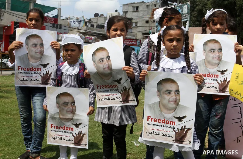 Palestinian demonstrators hold posters of Mohammad El Halabi, World Vision's manager of operations in Gaza who was accused by Israel of funnelling millions of dollars in aid money to Hamas, during a protest in solidarity...