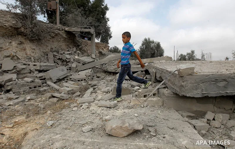 A Palestinian youth inspects the rubble of the home of Mohammed Abed Almajid El-Amaira, a Palestinian accused of involvement in a shooting attack that led to the death of a rabbi, after it was destroyed by Israeli milita...