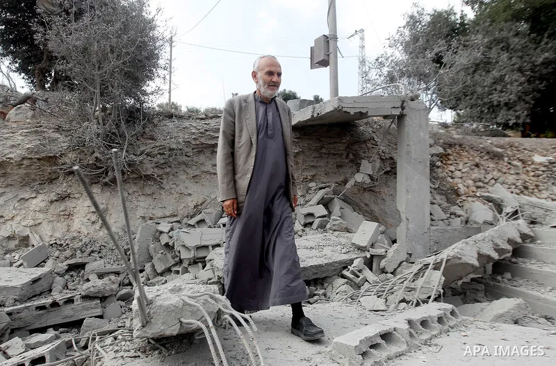 A Palestinian man inspects the rubble of the home of Mohammed Abed Almajid El-Amaira, a Palestinian accused of involvement in a shooting attack that led to the death of a rabbi, after it was destroyed by Israeli military...