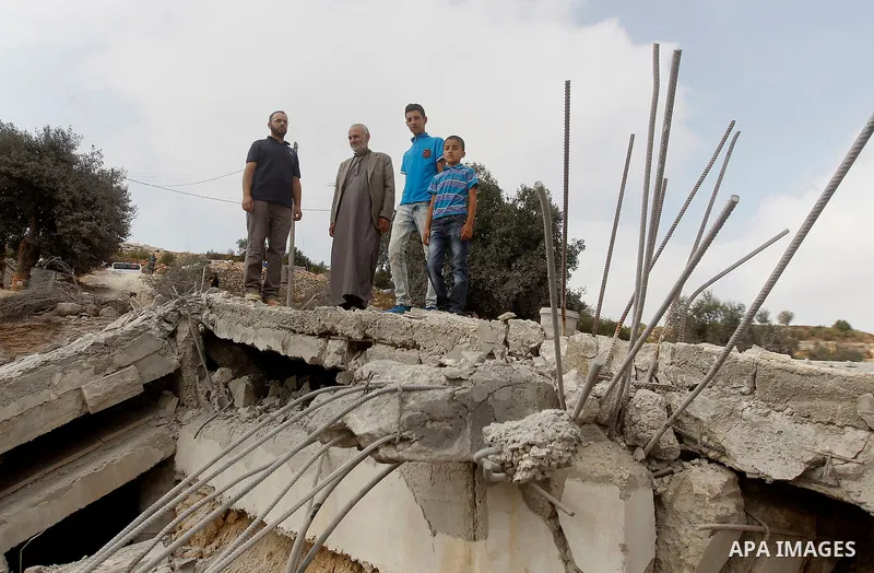 Palestinians inspect the rubble of the home of Mohammed Abed Almajid El-Amaira, a Palestinian accused of involvement in a shooting attack that led to the death of a rabbi, after it was destroyed by Israeli military on Au...