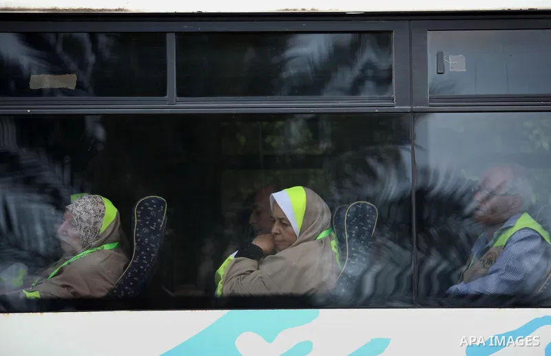 A Palestinian woman waves as she looks out of a bus window before leaving for Mecca for the annual Hajj pilgrimage, in Gaza City August 30, 2016. Photo by Ashraf Amra