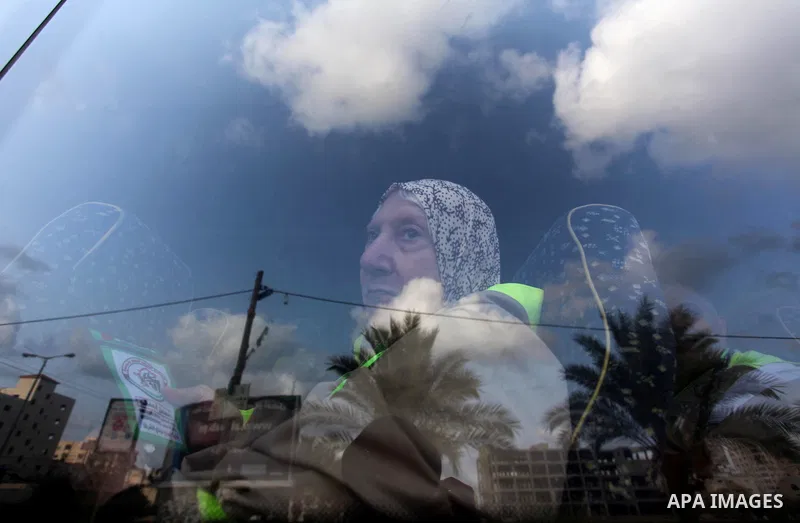 A Palestinian woman waves as she looks out of a bus window before leaving for Mecca for the annual Hajj pilgrimage, in Gaza City August 30, 2016. Photo by Ashraf Amra
