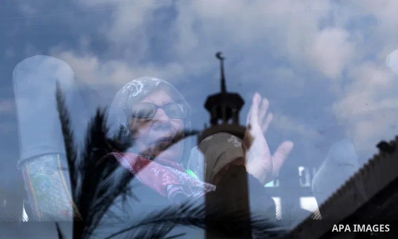A Palestinian woman waves as she looks out of a bus window before leaving for Mecca for the annual Hajj pilgrimage, in Gaza City August 30, 2016. Photo by Ashraf Amra