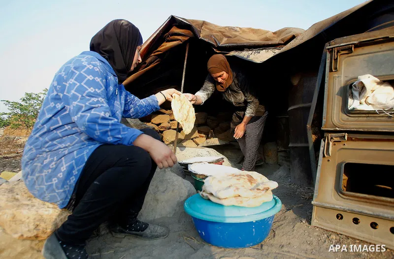 Palestinian women bake bread on a typical domed metal griddle for baking traditional flat bread, known locally in the region as the saj, in the West Bank village of Sosiya, south of Hebron, on September 1 2016, villages...