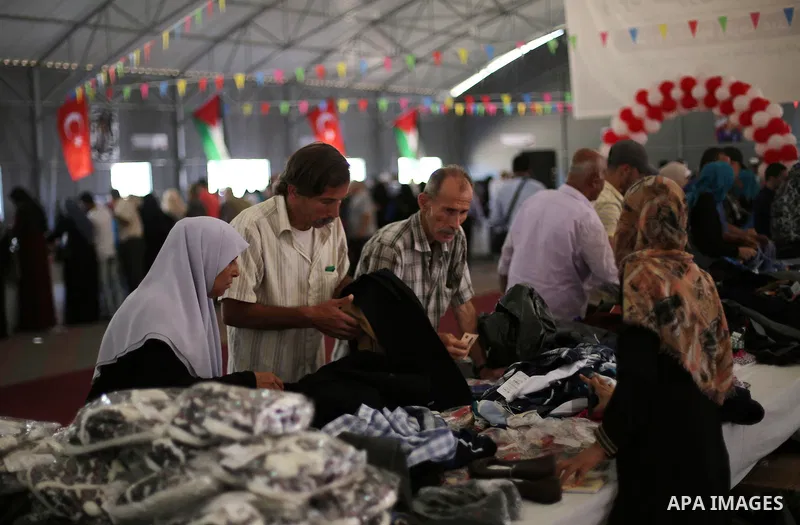Palestinians wait to receive aid from the Turkish Red Crescent organization, "Eid clothes" ahead of Eid al-Adha in Gaza City, on Sept. 04, 2016. Photo by Mohammed Asad