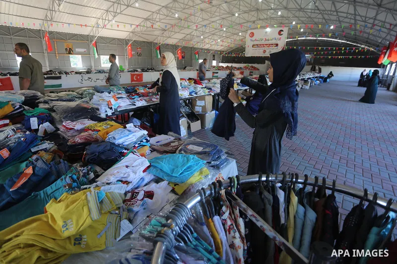 Palestinians wait to receive aid from the Turkish Red Crescent organization, "Eid clothes" ahead of Eid al-Adha in Gaza City, on Sept. 04, 2016. Photo by Mohammed Asad