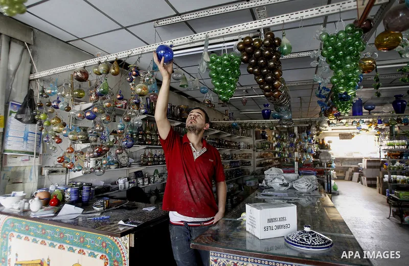 A Palestinian man uses types of glasses to decorate his factory in the West Bank city of Hebron, on Sep. 07, 2016. Hebron, the largest city in the West Bank has been officially awarded the title of World Crafts City, Rol...