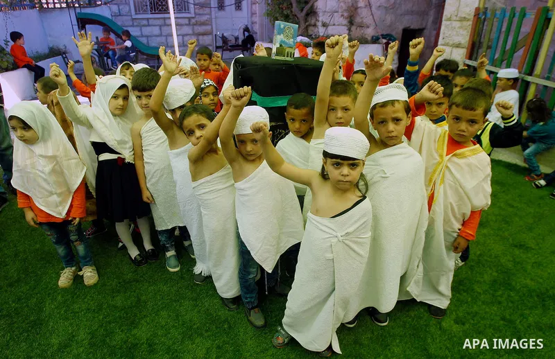 Palestinian children gather around a makeshift cube representing the holy Kaaba, in the West bank city of Hebnron, on Sept. 8, 2016, as part of training children how to perform Hajj pilgrimage. Muslims from around the wo...