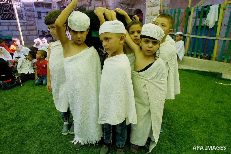 Palestinian children gather around a makeshift cube representing the holy Kaaba, in the West bank city of Hebnron, on Sept. 8, 2016, as part of training children how to perform Hajj pilgrimage. Muslims from around the wo...