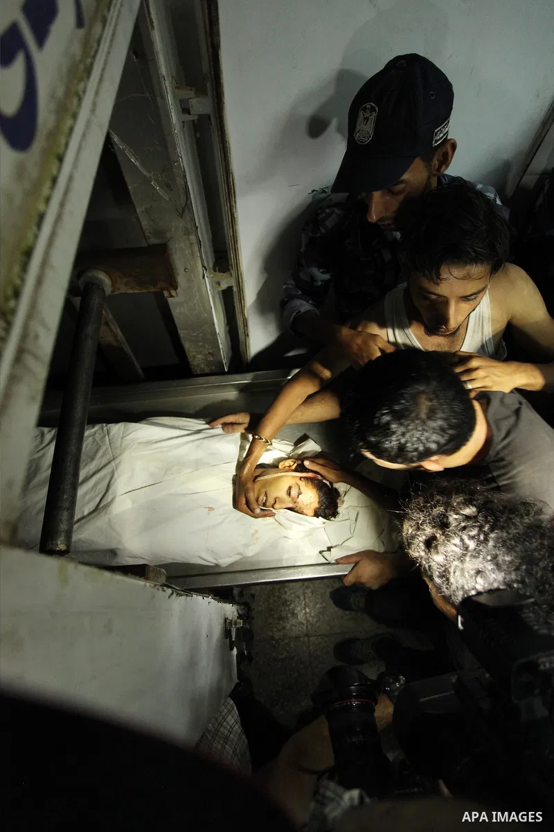 People gather around the body of Palestinian youth Abdulrahman Al-Dabag, who medics said was shot dead by Israeli troops on Friday, at a hospital morgue in the central Gaza Strip September 9, 2016. Photo by Ashraf Amra