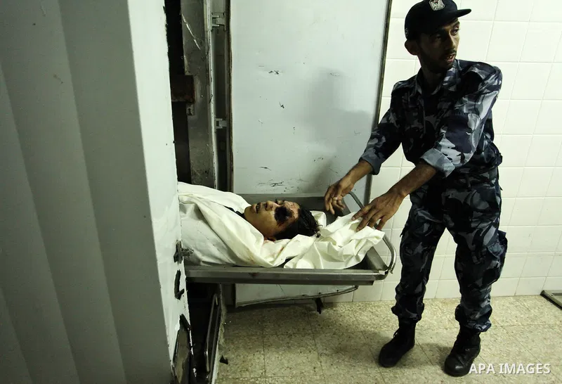 A Palestinian policeman inspects the body of Palestinian youth Abdulrahman Al-Dabag, who medics said was shot dead by Israeli troops on Friday, at a hospital in the central Gaza Strip September 9, 2016. Photo by Ashraf A...