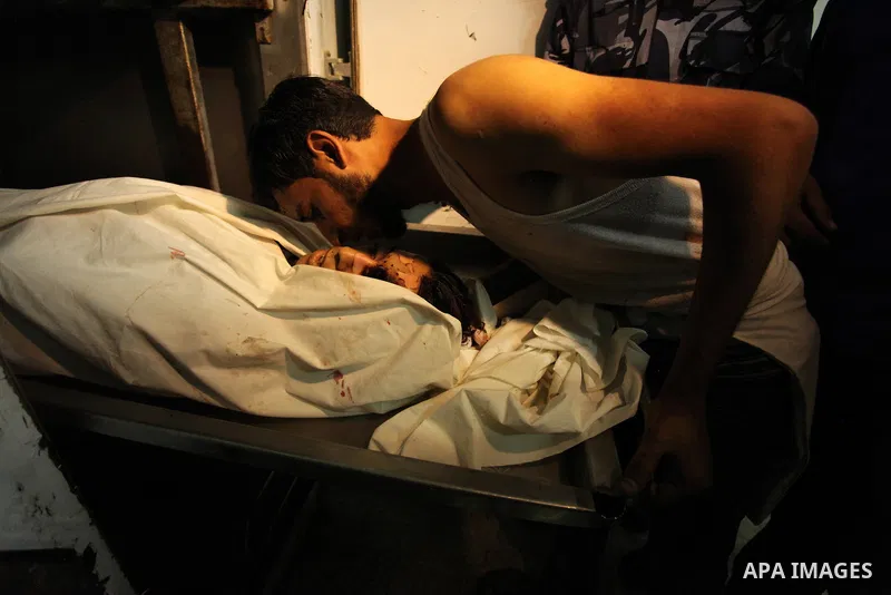 People gather around the body of Palestinian youth Abdulrahman Al-Dabag, who medics said was shot dead by Israeli troops on Friday, at a hospital morgue in the central Gaza Strip September 9, 2016. Photo by Ashraf Amra