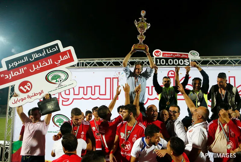 Players of Hebron's Ahly al-Khalil football club celebrate with the trophy after beating Hebron's Shabab al-Khalil club during Super Cup soccer match, in the West Bank city of Hebron, on Sep. 09, 2016. Photo by Wisam Has...