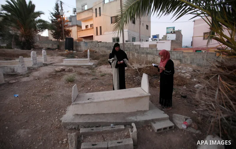 Palestinians visit the grave of their relative at a cemetery on the first day of of Eid al-Adha, or feast of the sacrifice, in the West Bank city of Nablus, on Sep. 12, 2016. Muslims around the world are celebrating Eid...