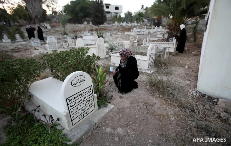 A Palestinian woman reads the Koran next to the grave of her relative at a cemetery on the first day of Eid al-Adha, or feast of the sacrifice, in the West Bank city of Nablus, on Sep. 12, 2016. Muslims around the world...