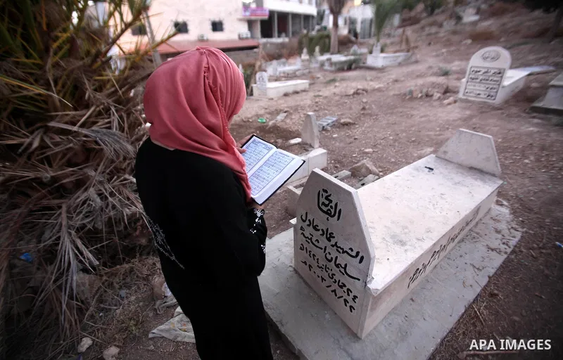 A Palestinian woman reads the Koran next to the grave of her relative at a cemetery on the first day of Eid al-Adha, or feast of the sacrifice, in the West Bank city of Nablus, on Sep. 12, 2016. Muslims around the world...