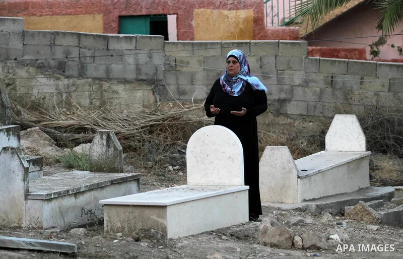 A Palestinian woman prays next to the grave of her relative at a cemetery on the first day of Eid al-Adha, or feast of the sacrifice, in the West Bank city of Nablus, on Sep. 12, 2016. Muslims around the world are celebr...