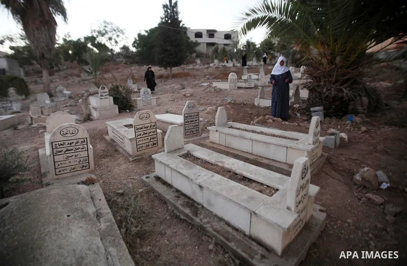 Palestinians visit the grave of their relative at a cemetery on the first day of of Eid al-Adha, or feast of the sacrifice, in the West Bank city of Nablus, on Sep. 12, 2016. Muslims around the world are celebrating Eid...