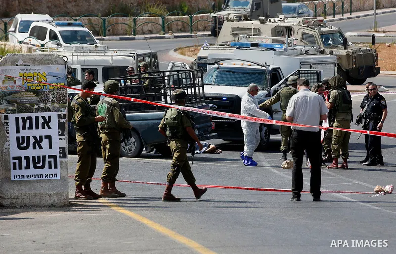 Israeli security forces gather around the body of Palestinian Fares Khadour, whom the Israeli military said was shot dead by Israeli forces after he rammed a car into a bus stop near the Jewish settlement of Kiryat Arba...