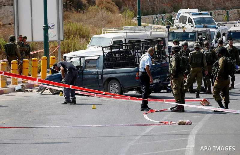 Israeli security forces gather around the body of Palestinian Fares Khadour, whom the Israeli military said was shot dead by Israeli forces after he rammed a car into a bus stop near the Jewish settlement of Kiryat Arba...