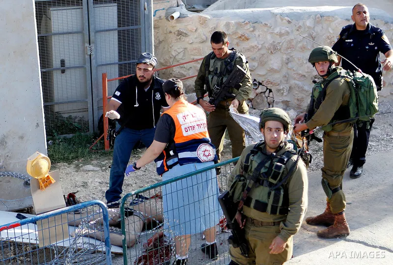 Israeli soldiers cover the body of a Palestinian who was shot dead after reportedly carrying out a stabbing attack on a soldier near the Jewish settler enclave of Tal Rumeda in the city centre of the West Bank town of He...