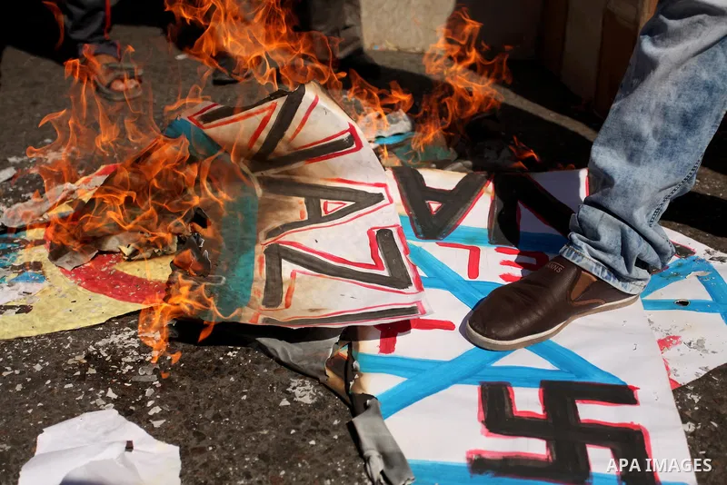 Palestinians burn posters bearing Israeli flag during a protest demanding release the prisoners in Israeli jails, in front of Red cross office in Gaza city, on Sept. 19, 2016. Photo by Ashraf Amra