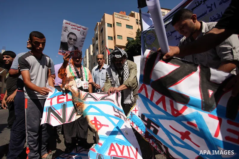 Palestinians burn posters bearing Israeli flag during a protest demanding release the prisoners in Israeli jails, in front of Red cross office in Gaza city, on Sept. 19, 2016. Photo by Ashraf Amra
