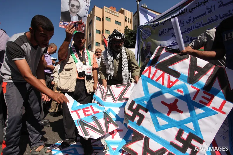 Palestinians burn posters bearing Israeli flag during a protest demanding release the prisoners in Israeli jails, in front of Red cross office in Gaza city, on Sept. 19, 2016. Photo by Ashraf Amra