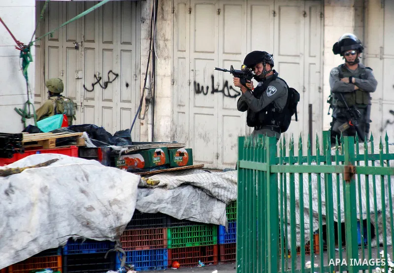 A member of Israeli security forces aims his weapon towards Palestinian protesters during clashes following two Palestinians were shot dead during a stabbing attack against Israeli border police in the West Bank city of...