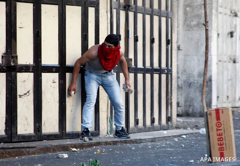 A Palestinian protester hurls stones towards Israeli troops during clashes following two Palestinians were shot dead during a stabbing attack against Israeli border police in the West Bank city of Hebron on September 19,...