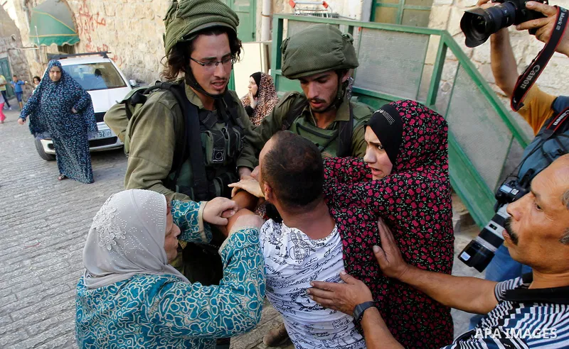 Israeli soldiers detain a Palestinian during a searching raid by Israeli troops, in the West Bank city of Hebron September 20, 2016. Photo by Wisam Hashlamoun