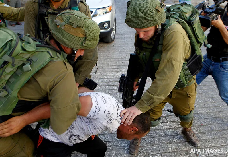 Israeli soldiers detain a Palestinian during a searching raid by Israeli troops, in the West Bank city of Hebron September 20, 2016. Photo by Wisam Hashlamoun