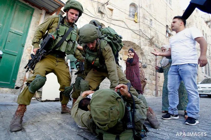 Israeli soldiers detain a Palestinian during a searching raid by Israeli troops, in the West Bank city of Hebron September 20, 2016. Photo by Wisam Hashlamoun