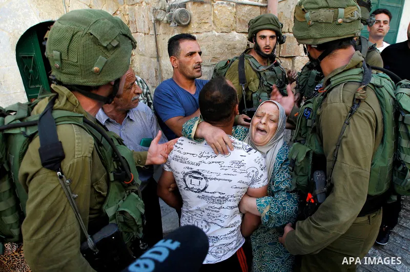 Israeli soldiers detain a Palestinian during a searching raid by Israeli troops, in the West Bank city of Hebron September 20, 2016. Photo by Wisam Hashlamoun