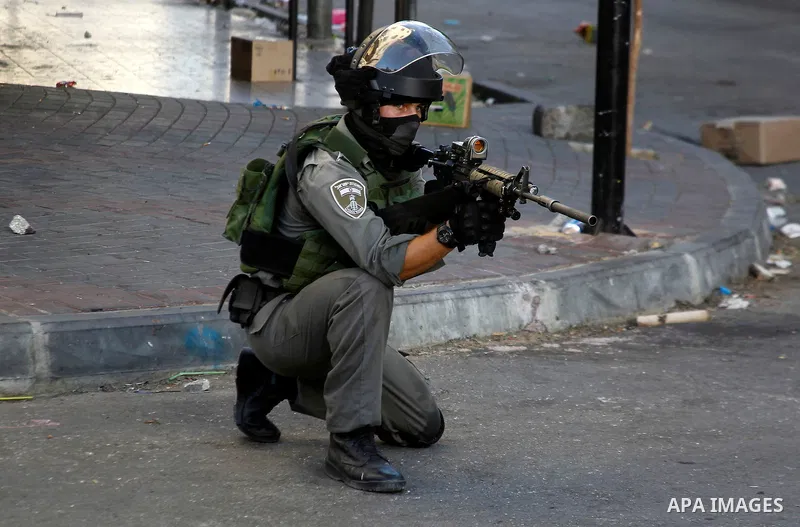 A member of Israeli security forces aims his weapon towards Palestinian protesters during clashes in the West Bank city of Hebron on September 20, 2016. Photo by Wisam Hashlamoun