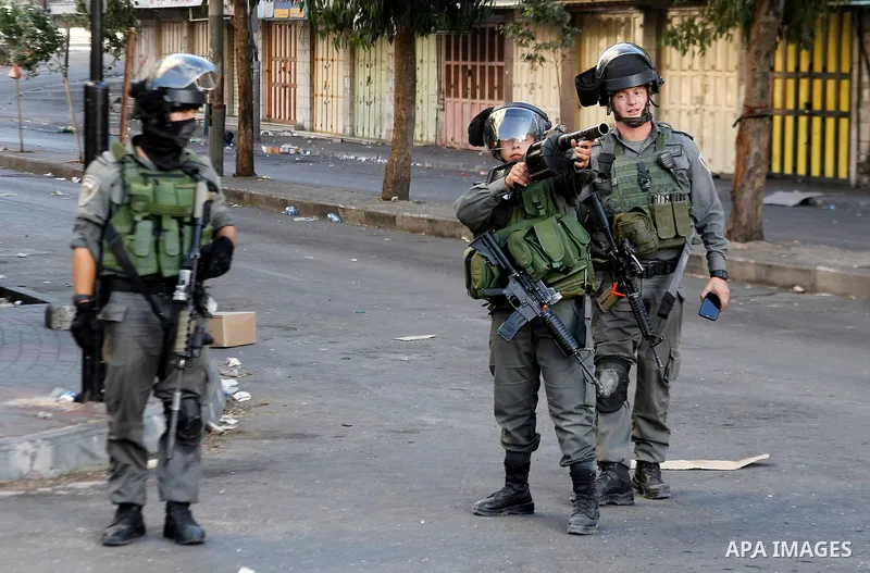 A member of Israeli security forces aims his weapon towards Palestinian protesters during clashes in the West Bank city of Hebron on September 20, 2016. Photo by Wisam Hashlamoun