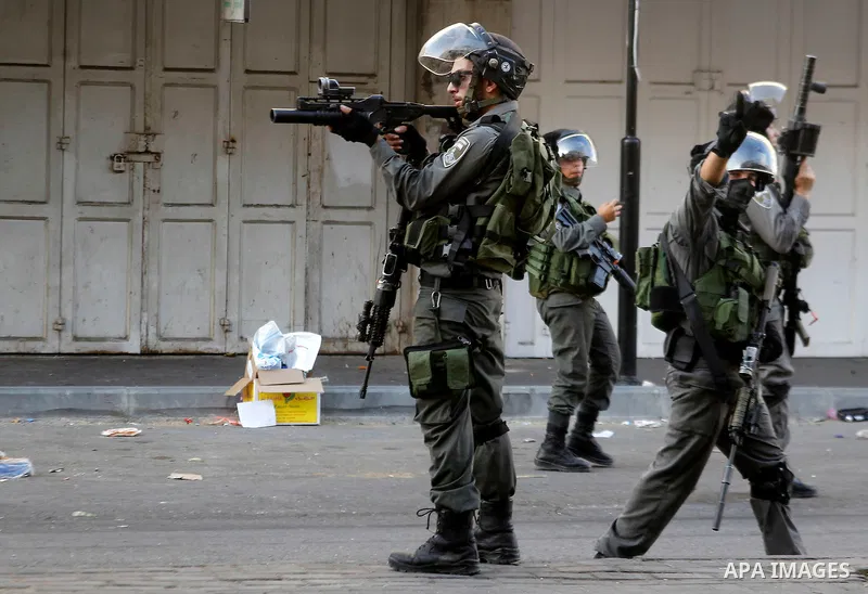 A member of Israeli security forces aims his weapon towards Palestinian protesters during clashes in the West Bank city of Hebron on September 20, 2016. Photo by Wisam Hashlamoun